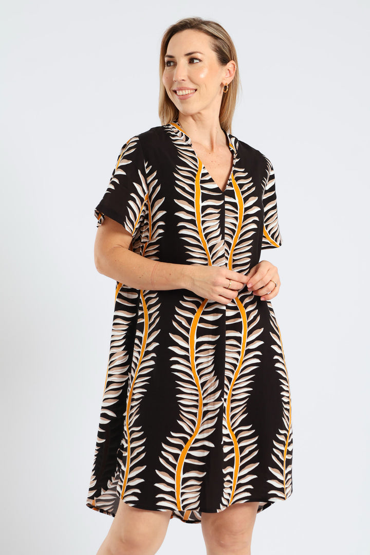 Woman wearing a black and white patterned dress with yellow accents on a light gray background